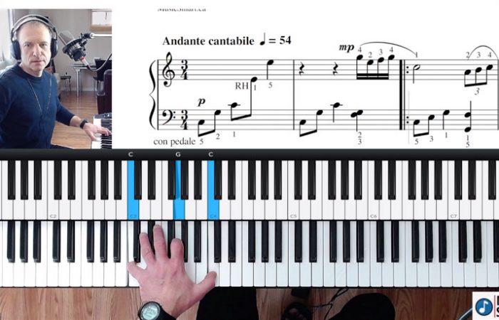 Computer screen showing online piano lesson with teacher at the keyboard, hands on piano and sheet music