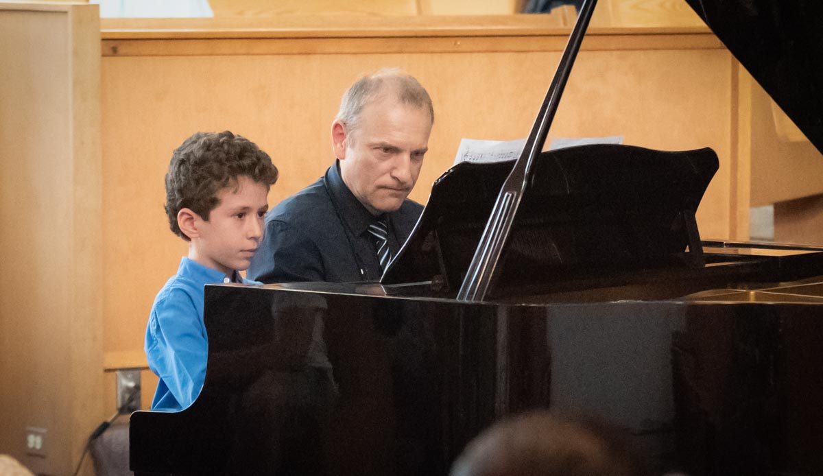 Piano duet teacher- young boy Artgate student playing, focusing on their sheet music