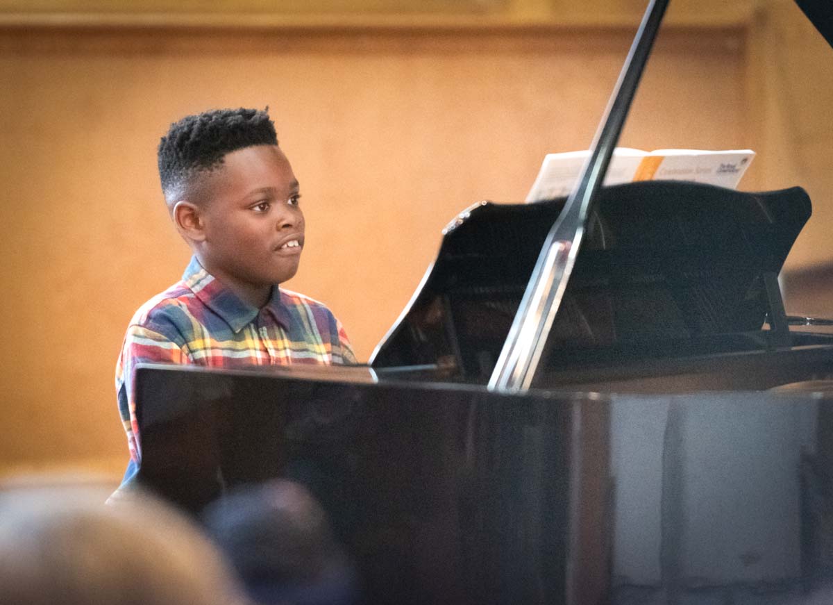 Black young boy piano student playing in Music Smart concert